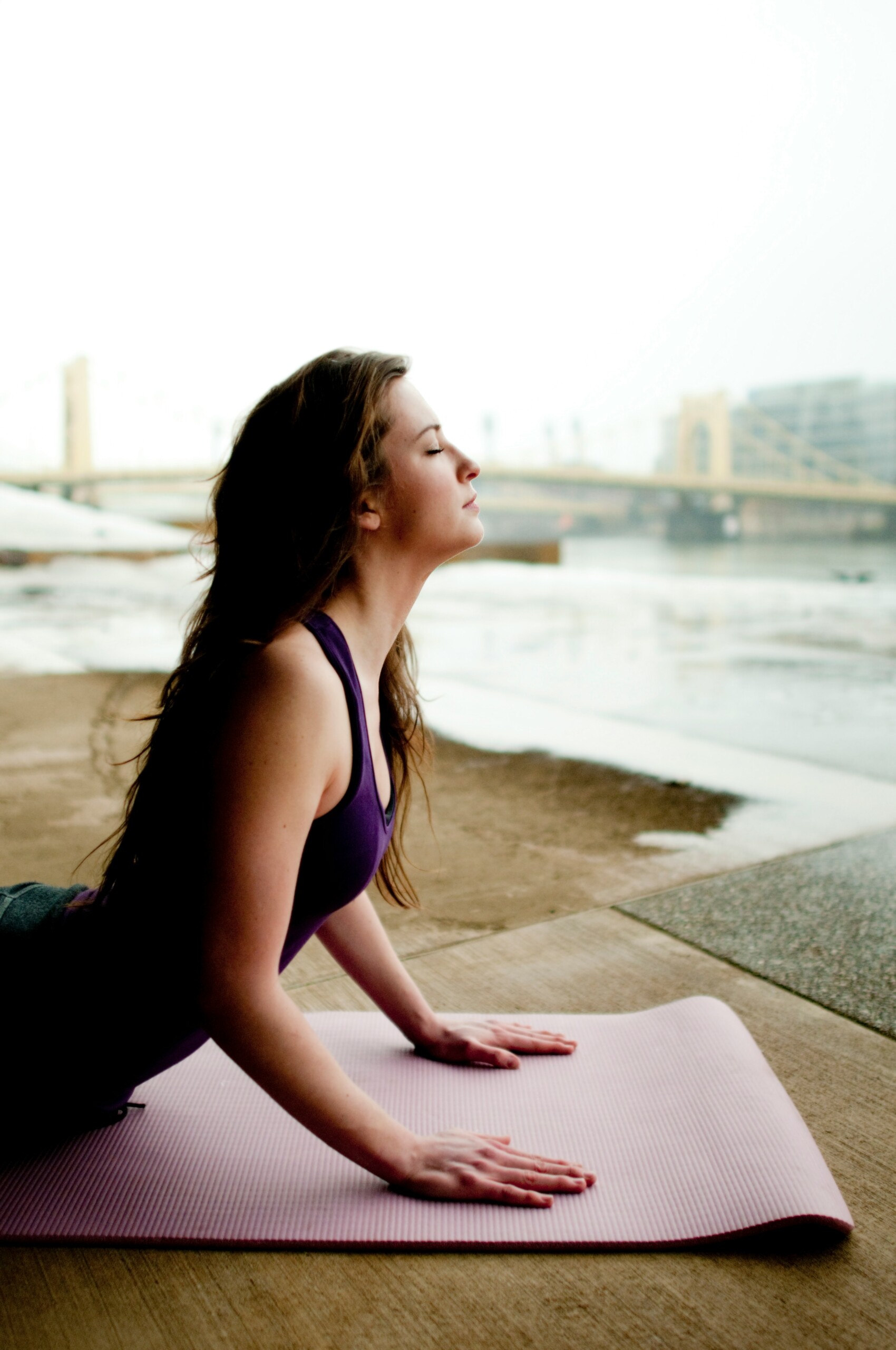 women in purple fitness wear with her eyes closed. she is in a pilates pose