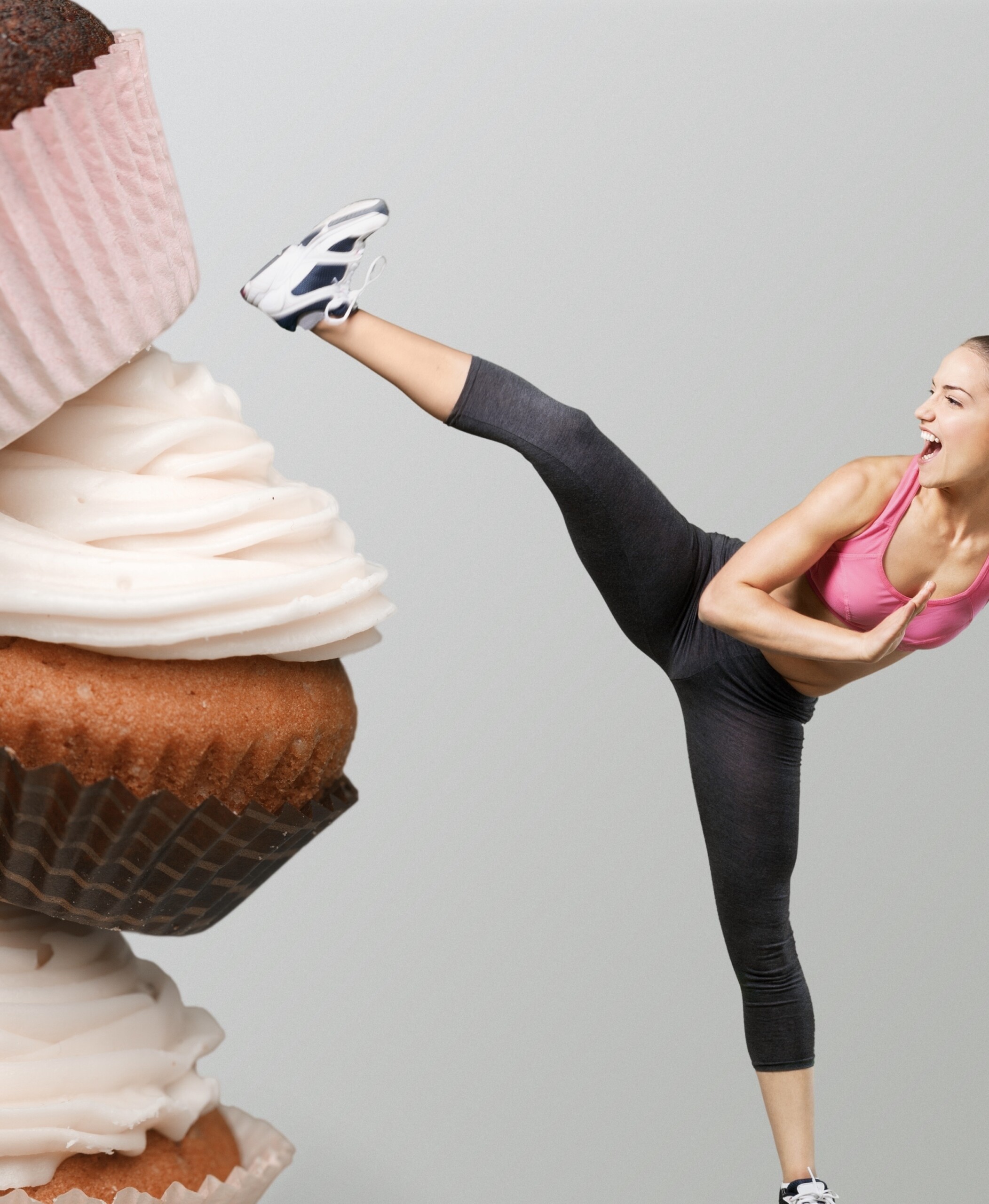 stack of cupcakes with woman in fitness wear kicking at the cupcakes