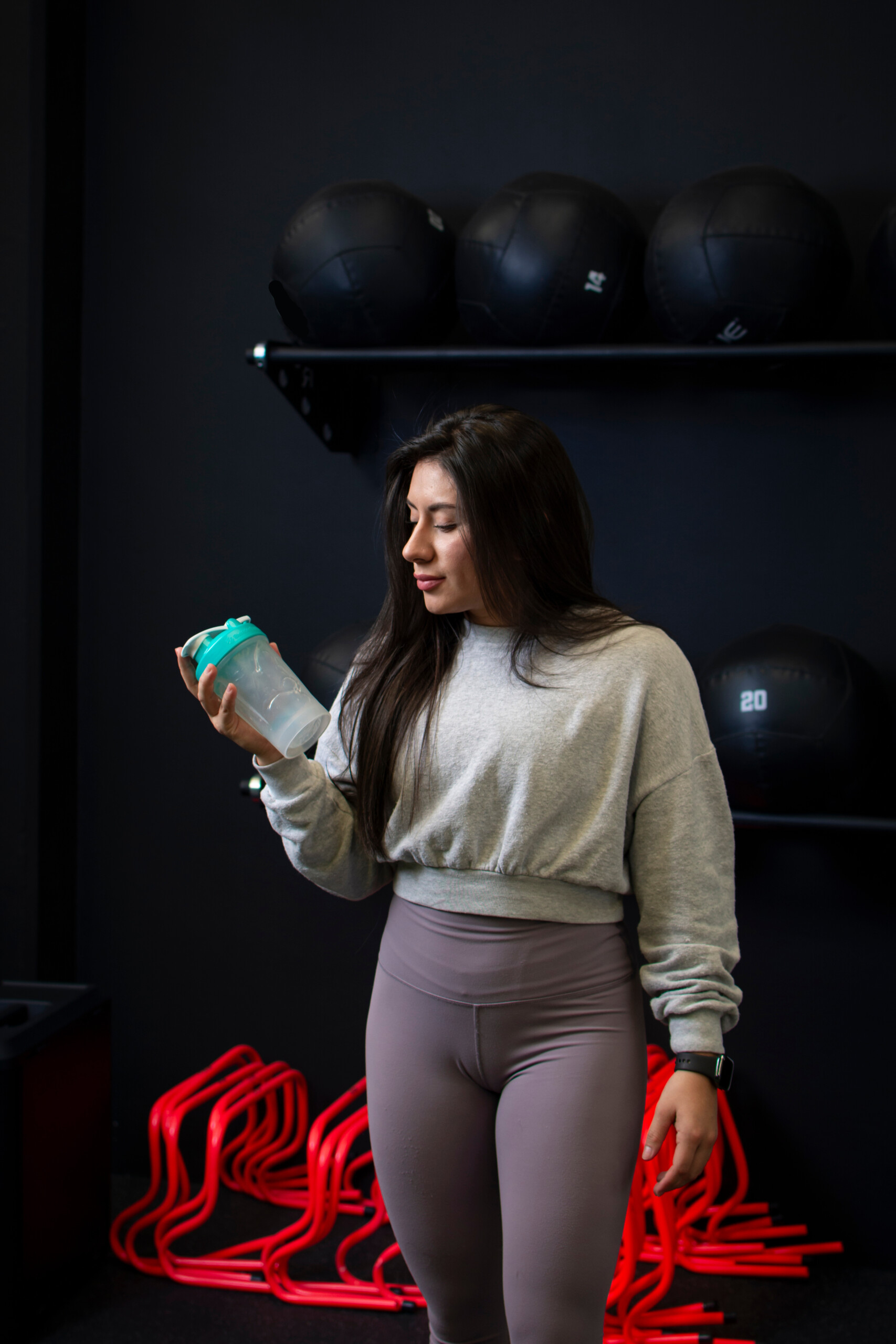 woman in fitness wear with empty shaker cup looking down at it